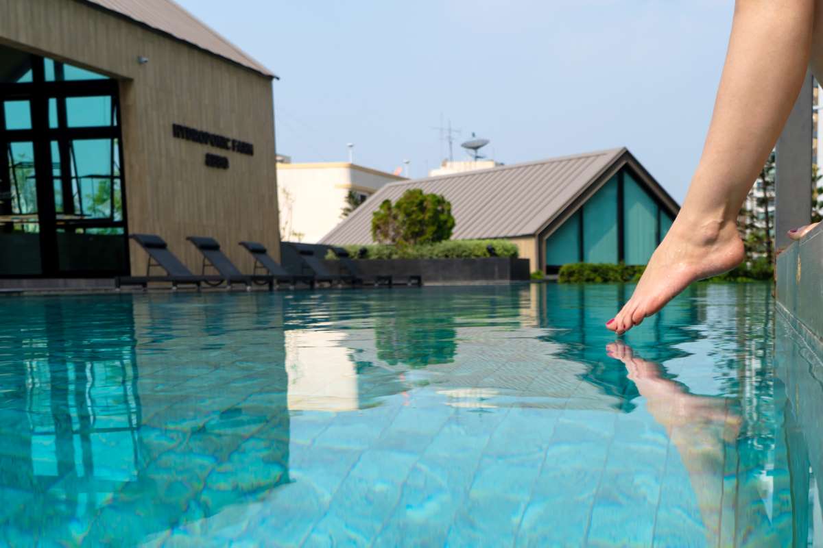 Pool chemistry under regional regulations — technician testing water temperature, pH, and chlorine to meet state-specific limits